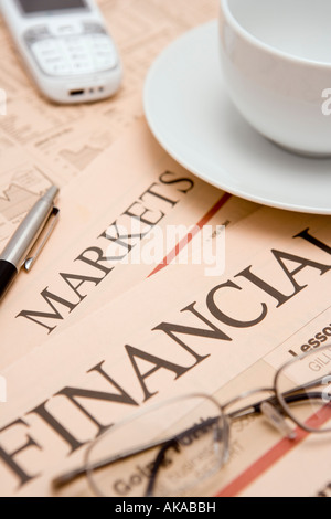 Business pagine del giornale studiando le notizie finanziarie quote delle scorte e dei mercati finanziari con caffè bicchieri penna telefono mobile Foto Stock