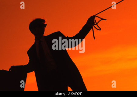 Imprenditore silhouette al tramonto tenendo una corda e una valigetta Foto Stock