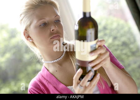 Donna che guarda la etichetta sulla bottiglia di vino Foto Stock