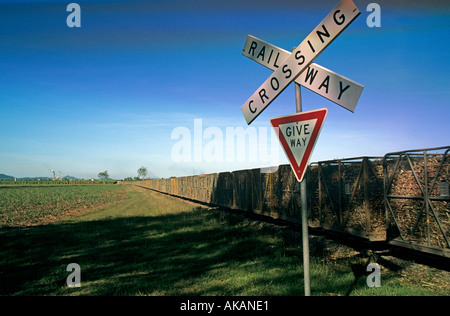 Incrocio ferroviario segno con treni e carrozze di canna da zucchero nel Queensland Australia Foto Stock
