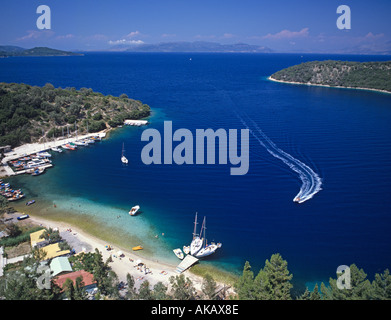 Vista di una grande baia blu con yacht ormeggiati intorno al piccolo molo e una barca veloce di entrare a velocità Spartahori ISOLE IONIE Grecia Foto Stock