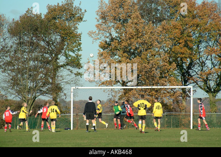 Partita di calcio in corso sul campo verde villaggio vista posteriore dell'arbitro a ragazzi adolescenti sport gioco di calcio Mountnessing Brentwood Essex Inghilterra Foto Stock