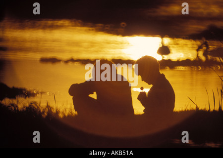 Due ragazzi giocare su un argine al tramonto Foto Stock