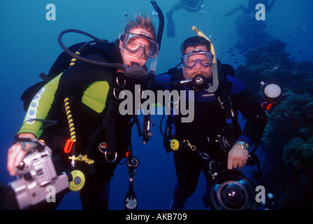 Come amici un maschio e femmina sub pongono insieme come essi portano fotocamera subacquea e apparecchiature video Foto Stock