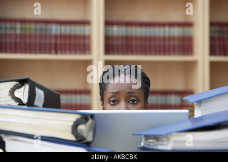 Lavoratore di ufficio utilizzando laptop seduti dietro pile di documenti in ufficio, sezione elevata Foto Stock