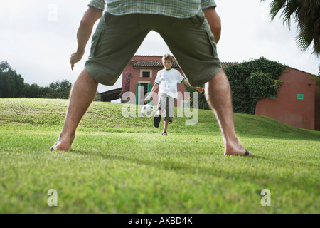Padre e figlio (5-6) giocando a calcio nel cortile posteriore Foto Stock