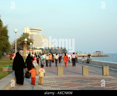 Famiglie godendo una gita sulla Corniche a Doha in Qatar con il landmark Doha Sheraton Hotel in distanza. Foto Stock