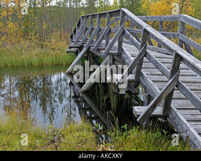 Ponte di legno su un fiume di ormeggiare nel paesaggio forestale in Lapponia, Finlandia Foto Stock