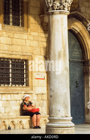 L' Europa sudorientale, Croazia, Dubrovnik, senior donna seduta di fronte Rectoras palace Foto Stock