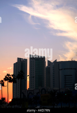 Il sole tramonta dietro alcuni degli edifici alti a Doha in Qatar Foto Stock