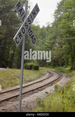 Attraversamento ferroviario segno con le vie della curvatura intorno all'angolo in background Foto Stock