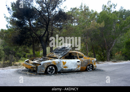 Auto bruciata ( Toyota Celica ) su una strada lungo una foresta Foto Stock