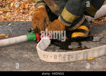 Un incendio fighter ai comandi di una valvola Y su un hoseline per la fornitura di acqua per altri vigili del fuoco sulla scena di emergenza Foto Stock