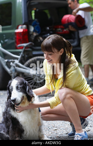 Donna con cane all'aperto, uomo auto caricamento in background Foto Stock