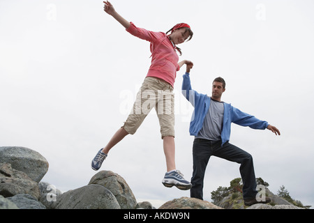 Giovane holding hands saltando sulle rocce Foto Stock