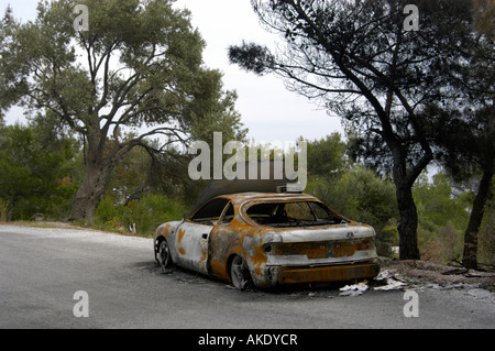 Auto bruciata ( Toyota Celica ) su una strada lungo una foresta Foto Stock