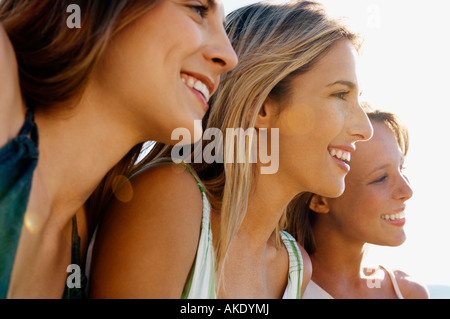 Tre giovani donne seduti fianco a fianco cercando di visualizzare, chiudere fino, la testa e le spalle Foto Stock