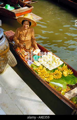 Un venditore al Mercato Galleggiante di Damnoen Saduak 100 km sud ovest di Bangkok in Thailandia offre frutta preparata piatti da la sua barca Foto Stock
