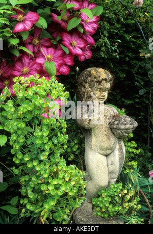 Frith Lodge Sussex Country Garden cottage in estate Clematis Ville de Lyon e Euphorbia piccola statua come punto focale Foto Stock