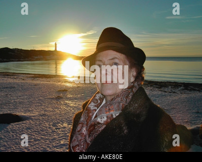 Donna anziana godendo di una passeggiata sulla riva del mare nel sole di setting Varberg in Svezia Foto Stock