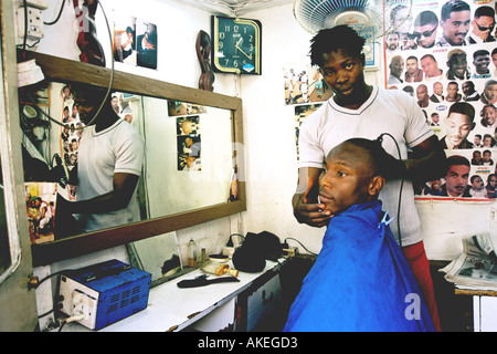 Barbiere locale nel centro cittadino di Obalende Stato di Lagos. Giovane uomo è ottenere il suo taglio di capelli di fronte ad un grande specchio. Foto Stock