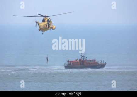Un mare di RAF Re Salvataggio in elicottero winching su un RNLI scialuppa di salvataggio Foto Stock
