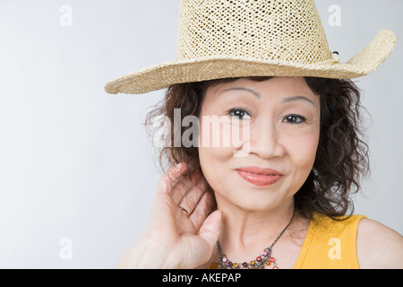 Ritratto di un senior donna che indossa un cappello di paglia e posa Foto Stock
