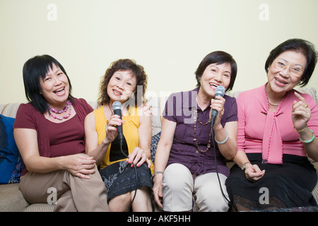 Tre le donne anziane e una donna matura di cantare davanti a microfoni Foto Stock