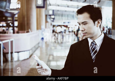 Close-up di un imprenditore tenendo un diario tascabile in un aeroporto Foto Stock