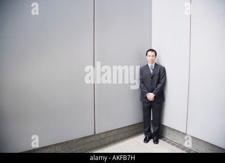 Imprenditore in piedi in un angolo con le mani giunte Foto Stock
