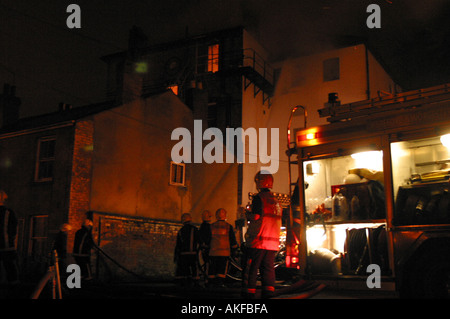 I vigili del fuoco al lavoro per tentare di spegnere un incendio in un piano superiore piatta dopo l'edificio preso fuoco Foto Stock