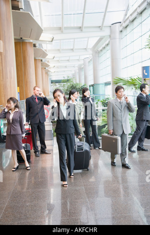 I dirigenti aziendali a parlare su telefoni cellulari e lasciando un aeroporto Foto Stock