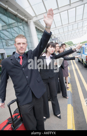 I dirigenti aziendali salutando un taxi in un aeroporto Foto Stock