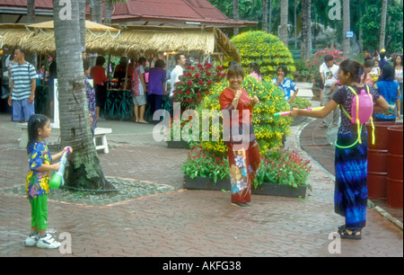 Songkran, Tailandese Anno nuovo, adulti in plastica con il cannone ad acqua e la pistola ad acqua back pack mirando a un bambino in divertimento al Nong Nooch Theme Park, Pattaya, Thailandia Foto Stock