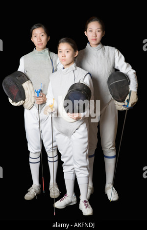 Ritratto di tre femminili schermitori tenendo la scherma maschere e lamine di scherma Foto Stock