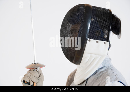 Close-up di una persona che indossa una maschera da scherma e tenendo una lamina di scherma Foto Stock