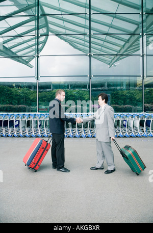 Profilo laterale di due imprenditori stringe la mano al di fuori di un aeroporto Foto Stock