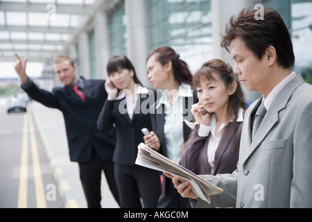 I dirigenti aziendali salutando un taxi in un aeroporto Foto Stock