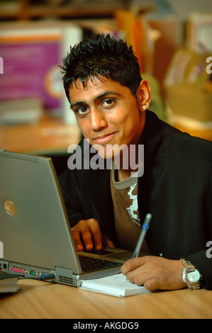 Un ragazzo adolescente lavorando su un computer portatile in un ambiente di ufficio REGNO UNITO Foto Stock