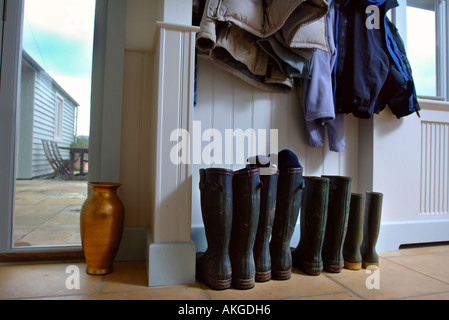 Stivali da pioggia e cappotti in un telaio di legno House Regno Unito Foto Stock