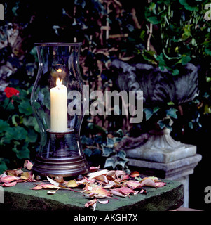 Foglie di autunno sul tavolo da giardino con urna di ferro e la candela accesa nella lanterna in vetro Foto Stock