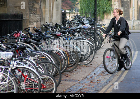 Uno studente lascia la sua bici in una fila di biciclette in rastrelliere in Oxford Foto Stock