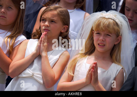 I bambini sorridere dolcemente e tenendo le mani in preghiera prima di effettuare la loro Prima Santa Comunione. Foto Stock