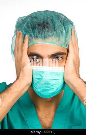 Close up scioccato medico chirurgo in verde scrubs e cappuccio chirurgico e maschera Foto Stock