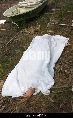 Piede della femmina caucasica corpo morto sporgenti da sotto il foglio bianco in Carolina del Sud palude USA, scena del crimine Foto Stock