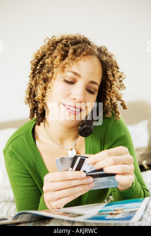 Donna al telefono scegliendo carta di credito Foto Stock