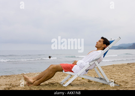 Uomo dorme in sedia a beach Foto Stock