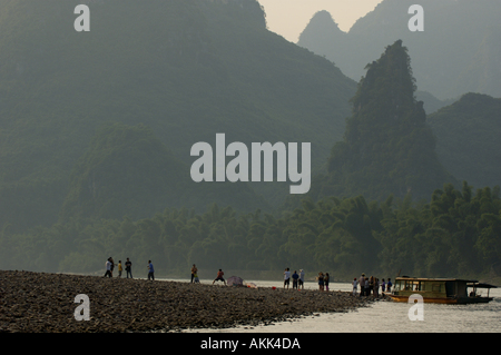 I passeggeri di un viaggio in barca di Li Jiang fiume fermatevi e guardate calcare picchi di montagna tra Xinping e Yangshuo, Cina Foto Stock