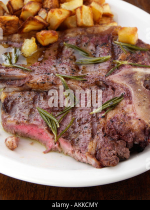 Una piastra di T bone steak con patate arrosto e rosmarino salsa di burro cibo editoriale Foto Stock