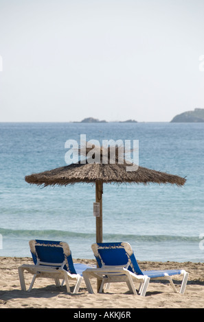 Ombrellone e due sedie a sdraio sulla spiaggia di Platja d'en Bossa, Ibiza Foto Stock